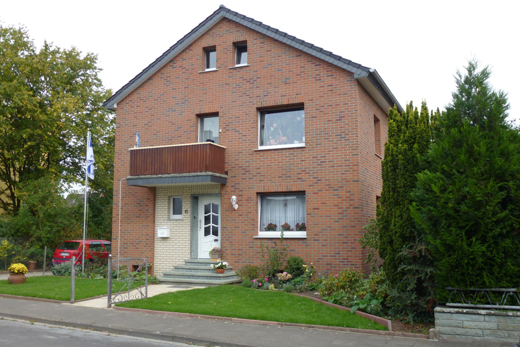 Haus mit Klinkern in hellrot und anthrazit und Haustür-Bereich in creme-weiß